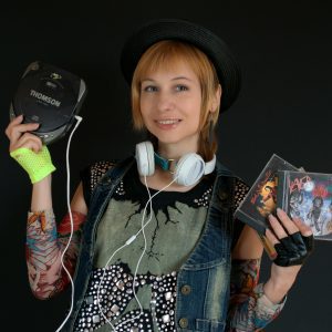 A Stylish Woman With A Retro Look Poses With CDs And A Portable CD Player, Celebrating 90s Music Culture.
