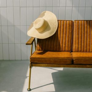 Elegant Chair With A Straw Hat And Slippers On A Sunny Day Against A Tiled Wall, Perfect For Lifestyle Shoots.