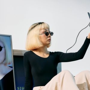 Chic Editorial Shot Featuring A Stylish Model With Vintage Electronics, Embracing A Trendy And Conceptual Look.