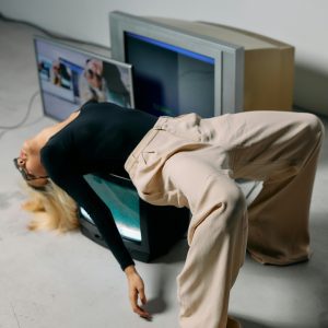 A Stylish Model Strikes An Eccentric Pose, Blending Fashion And Technology With A Vintage CRT TV.