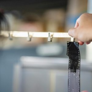 Close Up Of A Hand Pinning A Film Strip For Developing In A Darkroom.
