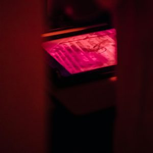 A Darkroom With Red Light Illuminating A Developing Photographic Print For Artistic Purposes.