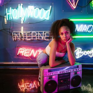 Young Woman In A Neon Lit Room With A Vintage Boombox, Embodying Vibrant Nightlife And Urban Culture.