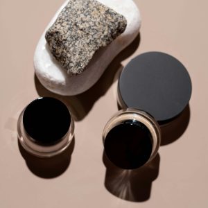 A Minimalist Flat Lay Of Beauty Products And Rocks, Emphasizing Natural Textures.