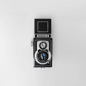 Top View Of A Classic Reflecta II Twin Lens Reflex Camera On A White Background.