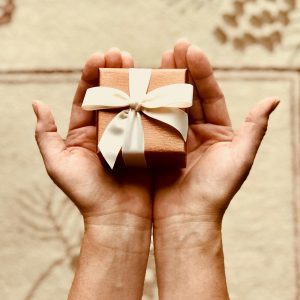 Close Up Of Hands Holding A Beautifully Wrapped Gift Box With A Ribbon, Perfect For Celebrations And Surprises.