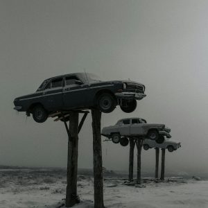 Vintage Cars Mounted On Wooden Poles In A Snowy, Foggy Winter Landscape, Capturing A Surreal Scene.