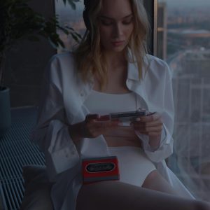 Young Woman In A White Outfit Listening To Music With A Retro Cassette Player Near A Window.