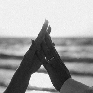 Monochrome Photo Of Hands Touching Affectionately By The Ocean.