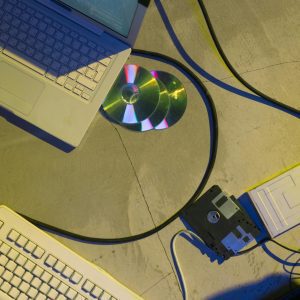 Flat Lay Of Vintage Laptop, CDs, Floppy Disk, And Wires Suggest A Retro Tech Theme.