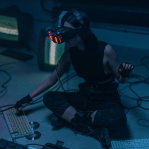 A Woman In A VR Headset And Gloves Interacts With Technology In A Dimly Lit Room.