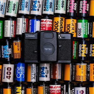 LOMO Camera Surrounded By Diverse Film Roll Brands, Showcasing Analog Photography Appeal.