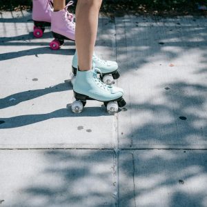 Two Women Roller Skating With Pastel Boots On A Sunny Sidewalk, Enjoying A Fun Outdoor Activity.
