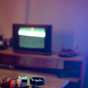 Vintage Living Room With Sushi, Gun, And A Glowing TV, Creating A Nostalgic And Moody Ambiance.