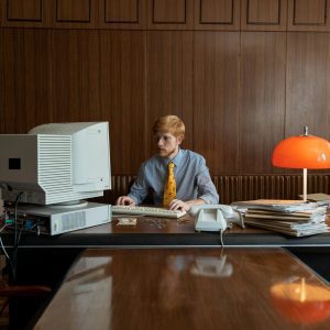 Vintage Office Environment With A Man Working On A Classic CRT Monitor And Desktop Computer Setup.