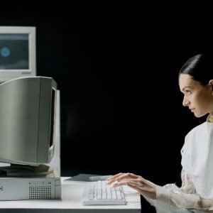 A Woman Typing On A Retro CRT Computer In A Modern Laboratory Setting.
