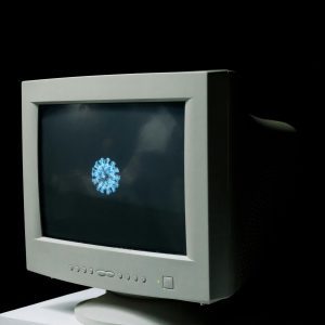 An Old CRT Monitor Displaying A Digital Representation Of A Virus On A Black Background.