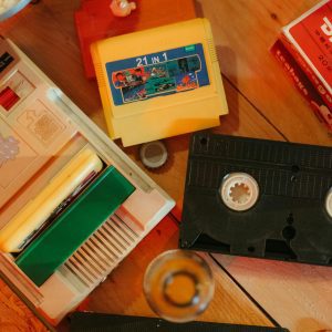 Vintage Gaming Console With Cartridges And VHS Tape On Wooden Surface, Nostalgic Theme.