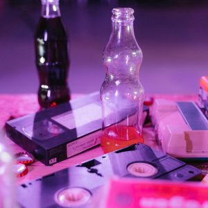 Vintage VHS Tapes And Colorful Soda Bottles On Display, Capturing Nostalgia And Retro Aesthetics.