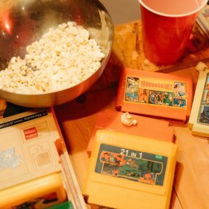 A Bowl Of Popcorn With Retro Video Game Cartridges And A Cup, Perfect For A Nostalgic Gaming Night.