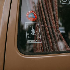 Close Up Of A Vintage Car Window Adorned With Rocket Themed Stickers And Curtains.