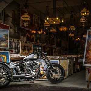 A Vintage Motorcycle Displayed In An Art Gallery Surrounded By Paintings And Chandeliers.