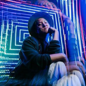 Stylish Portrait Of A Person In A Hat Surrounded By Vibrant Neon Lights, Exuding A Nightlife Vibe.