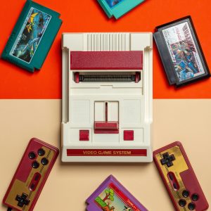 Flat Lay Of Vintage Video Game Console With Colorful Cartridges On Vibrant Background.