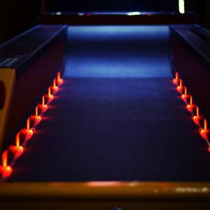A Vibrant Neon Lit Bowling Lane Creating A Dynamic And Dark Atmosphere Indoors.
