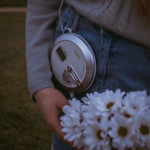 Person Holding Daisies With A Vintage CD Player, Showcasing Retro Style Fashion.