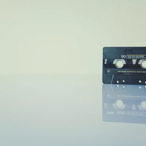 Retro Cassette Tape On A Reflective Surface, Evoking Nostalgia And Vintage Music Vibes.