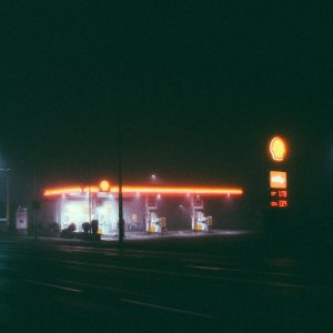 A Foggy Night Scene Of An Illuminated Gas Station, Featuring Vibrant Neon Lights.