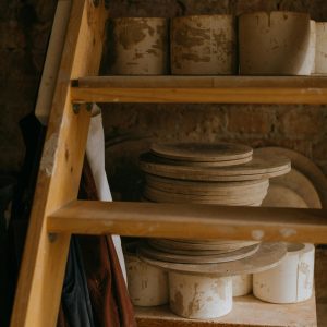 Rustic Clay Pots Stacked On A Wooden Ladder In A Cozy Workshop Setting.