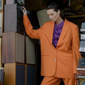 Stylish Woman In Orange Outfit Posing Among Vintage Cassette Players And Speakers.