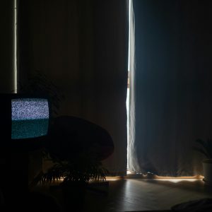 A Dimly Lit Living Room With Static On The TV And Curtains Drawn, Creating A Moody Atmosphere.