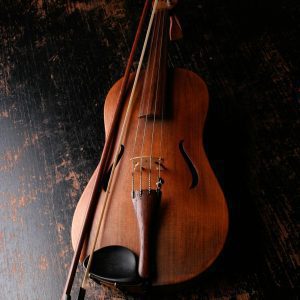 A Beautifully Crafted Violin Rests On A Dark Wooden Surface, Evoking A Classic And Artistic Mood.